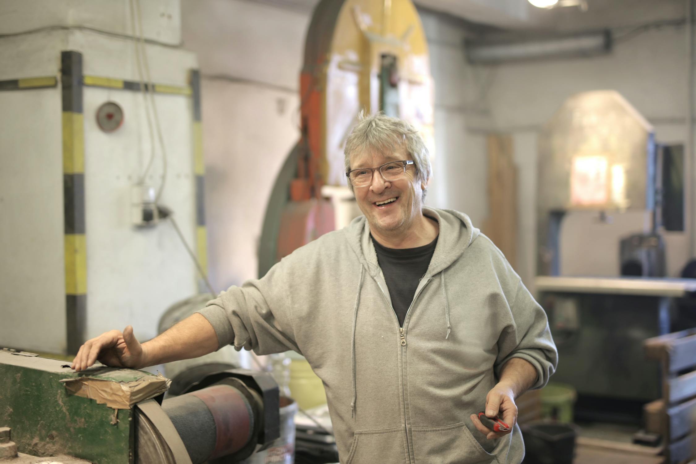 Trabajador experimentado sonriendo en su taller, representando las PYMEs y oficios de Latinoamerica