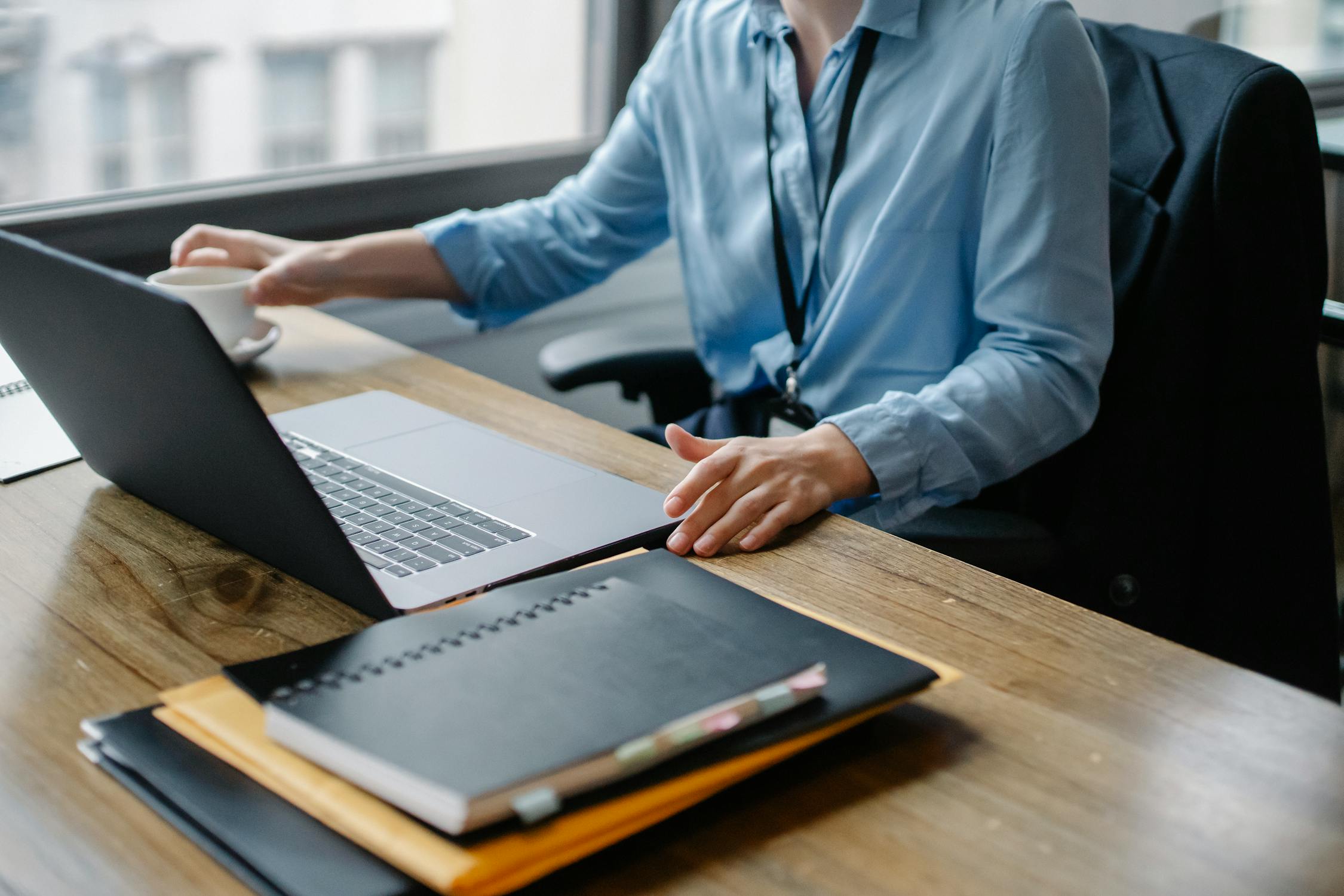 Profesional trabajando en su laptop con una taza de cafe en un espacio de trabajo real